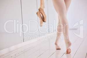 Ballet dancer with worn, broken and torn pantyhose, tights or leggings after her difficult or long practice class. Low angle of a ballerina holding pointe shoes in hand showing dedication to art form