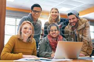 When they work together they will succeed together. Portrait of a cheerful young group of students working together using a laptop to study for exams inside of a library.