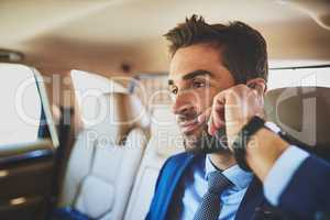 I wonder what will he be up to today. a confident young businessman talking on his cellphone while being seated in the back of a car.