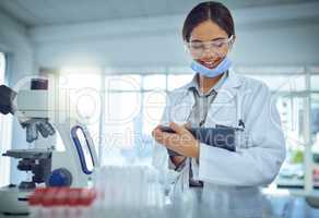 Recording all the facts and findings. a female scientist using a digital tablet in a lab.