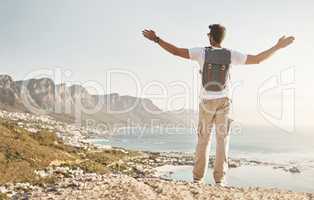 Feel the freedom. Rearview shot of an unrecognizable young man standing with his arms outstretched while hiking in the mountains.