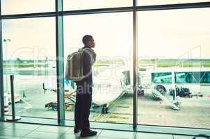 Waiting till we take flight. a man looking through the window at an airport.