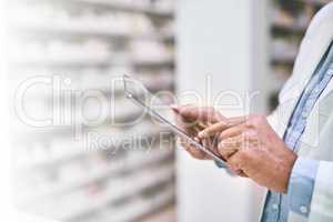 Thats another sale made. a unrecognizable pharmacist making notes on a digital tablet in a pharmacy.