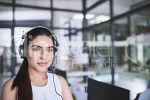 One has to keep calm when dealing with customers. Portrait of a cheerful businesswoman talking to a customer using a headset while looking at the camera.
