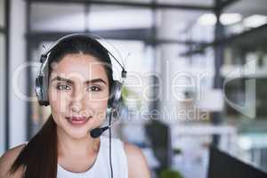 Nothing can distract her from her job. Portrait of a cheerful businesswoman talking to a customer using a headset while looking at the camera.