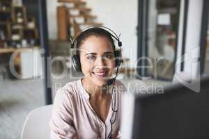 This job has you busy all the time. Portrait of a cheerful businesswoman talking to a customer using a headset while looking at the camera.