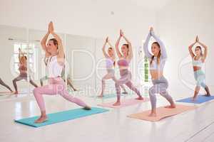 Yoga, class and warrior pose of women exercising and stretching during their morning workout or exercise. Group of calm, fit and active woman training together living a healthy balanced lifestyle.