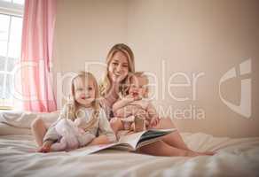 Once upon a time there lived a little princess. an adorable family of three reading a book together on the bed at home.