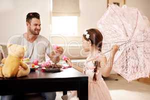 Cheers, my princess. a father and his little daughter having a tea party together at home.