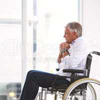 Theres a lot going through his mind. a focused mature man sitting in a wheelchair while contemplating inside a clinic.