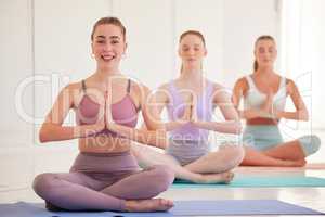 Yoga, health and wellness group of woman in calm, peaceful and relaxing mediation or exercise in a studio. Spiritual and fit women on a mat practicing inner healing, peace and namaste gesture.
