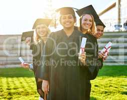 Diligence pays off. Portrait of a group of students holding their diplomas on graduation day.