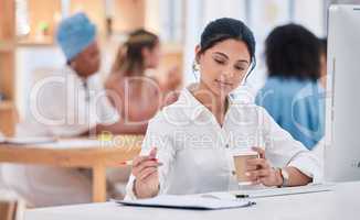 Business intern writing notes, planning ideas and brainstorming while working on strategy in a startup agency. Organized young woman drinking coffee, developing goals and thinking of innovation