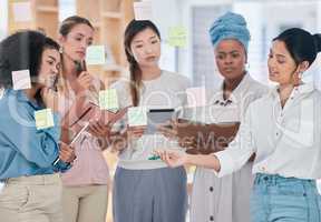 Female planning, strategy and project management with sticky notes or training in informal business collaboration meeting, discussion or idea sharing. Multicultural women working or organizing