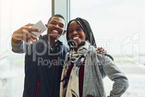 Well be documenting everything on our trip. two young people taking a selfie together at the airport.