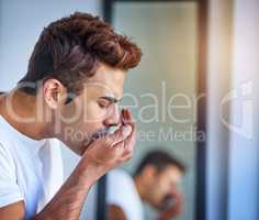 Maybe its time to switch to a different mouth wash. a handsome young man smelling his breath during his morning grooming routine.