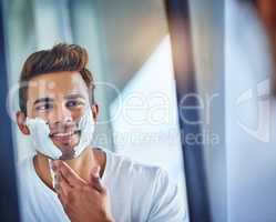 Grooming to make sure he gives his best first impression. a handsome young man shaving his facial hair in the bathroom.