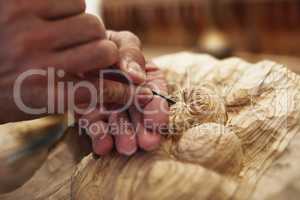 Applying the finishing touches. an artist carving something out of wood.