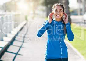 Get your workout groove on. a sporty young woman listening to music while exercising outdoors.