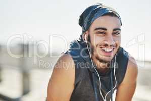 Music gets me moving faster. Portrait of a sporty young man listening to music while exercising outdoors.