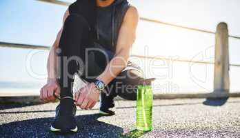 Gear up for another round. Closeup shot of an unidentifiable man tying his laces while exercising outdoors.