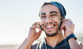 Deciding on the tunes to keep him moving. a sporty young man listening to music while exercising outdoors.