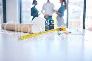 Architecture, construction and building with plans, blueprints and tape measure on a desk in an architect office. Closeup of engineer or contractor equipment on a table ready for planning and design