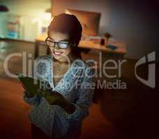 Staying in the know whatever time of the night. a young businesswoman using a digital tablet during a late night at work.