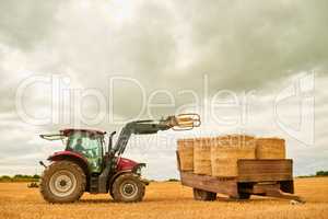 One on top of the other. a farmer stacking hale bales with a tractor on his farm.