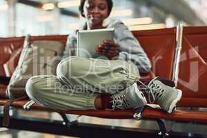 My tablet makes the wait seem shorter. a young woman using her digital tablet at the airport.