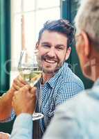 We need to do this more often. a cheerful young man and his mature father having a celebratory toast with wine glasses at home.