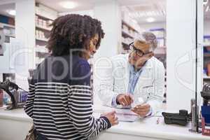 This will get you better in no time. a dedicated mature male pharmacist giving a customer prescription meds over the counter.