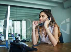 Sometimes anxiety gets the best of her. a young businesswoman biting her nails while talking on a phone in an office.
