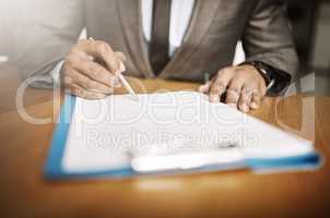 Making changes in the company. an unrecognizable businessperson signing papers inside of the office during the day.