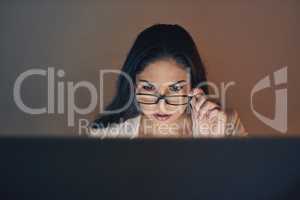 Focus and dedication gets her through the night. a young businesswoman using a computer during a late night at work.