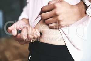 Keeping her glucose levels within a healthy range. Closeup shot of an unidentifiable businesswoman injecting her stomach.