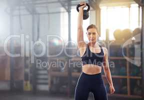 Strong, powerful woman doing kettlebell weight lift exercise, workout or training in wellness gym. Sports person holding or exercising with fitness equipment for muscle, strength or health portrait