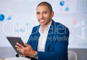 Successful financial businessman smiling while browsing on a digital tablet in the office. Portrait of a male professional accountant feeling positive after completing a deal or finishing a work task