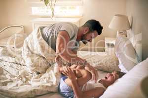 Bonding with his little joy. a father tickling his little son in bed at home.