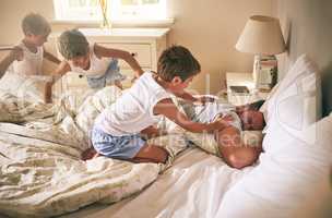 Wake up Dad, or get ready for a tickle attack. a little boy waking up his father from bed in the morning.