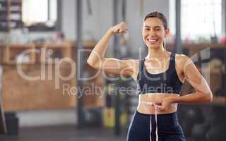 Slim, fit and weightloss with woman holding measuring tape around waist and flexing her muscles to celebrate losing weight and achieving her goal. Smiling female athlete happy about diet and exercise