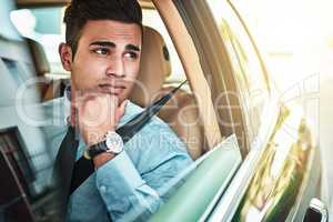 Hope this traffic doesnt make me late for work. a young businessman looking worried while driving a car.