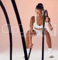 Fitness, battle ropes and active woman in a routine workout, training and exercise against pink studio background. Sporty, athletic and strong athlete exercising for cardio health and muscle strength