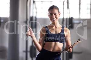 Thumbs up, personal trainer and fitness coach with gym clipboard to monitor health, weight loss and muscle growth. Portrait of excited woman and fit athlete supporting exercise, workout and training