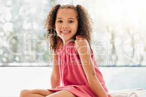 Happy child, cute curls and girl with adorable, sweet and happy smile relaxing at home. Portrait of comfortable, fun and young kid growing with healthy development, youth and adolescence
