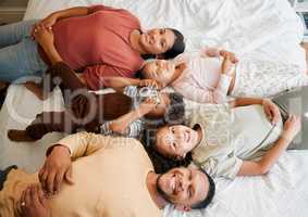 Fun family, children and parents bonding while lying on a bed in home bedroom from above. Portrait of playful, smiling and happy kids having fun with mother and father on weekend and making memories