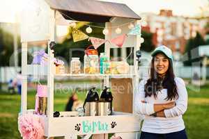 Desert takeaways. a cheerful young woman standing next to her baked goods stall while looking at the camera.