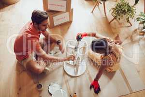 Recycle, thrift furniture and painter couple painting wooden table for new creative project in an apartment. Above view of man and woman working on DIY home improvement with a reusable craft object