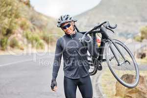 Cycling, bike trail and fitness man carrying his bicycle after riding along a countryside road. Happy male cyclist and athlete wearing a helmet, glasses and gear while training for a sports race