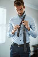 The way to make the perfect tie. a handsome young man dressing himself at home.